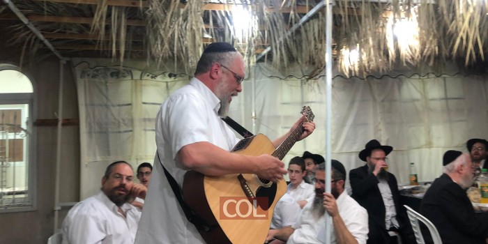 ר׳ אסי שפיגל והגיטרה המפורסמת כעת בהתוועדות בסוכת בית הכנסת  ׳מענדלס שול׳ בכפר חב״ד 