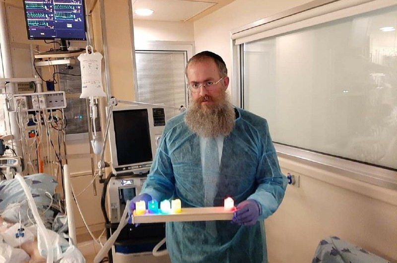 השליח בסביון הרב שמואל ביסטריצקי לבוש בסטריליות ליד מיטתו של תושב סביון המאושפז בטיפול נמרץ. הוא אירגן חנוכיית לדים והחולה שהיה בעבר מורדם ומונשם, בירך את הברכות