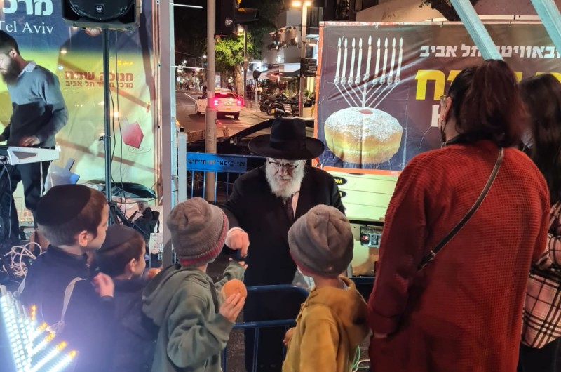 השליח הראשי בתל אביב, הרב יוסף גערליצקי מחלק 'דמי חנוכה' לילדים בהדלקה המרכזית בכיכר דיזנגוף בעיר, בהשתתפות קהל רב