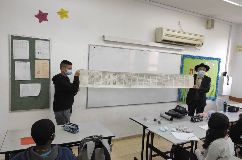 הרב יוסף הרטמן, המתנדב עשרות שנים בגימנסיה 'דרכא' בקריית מלאכי ומכין נערים לבר מצווה, מדגים לתלמידים איך ניראת מגילת אסתר על קלף