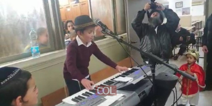 החייל בצבאות השם מיכל רוזמן בן ה-8 מנגן בשמחת פורים בבית הכנסת המרכזי בנחלת הר חב