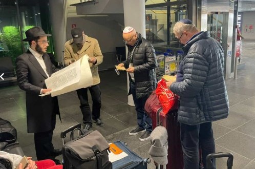 השליח בעיר הנופש יורמלה שבלטביה, הרב מענדי זילברשטרום, קורא בשיא המרץ מגילה לישראלים ומקומיים שנחתו בשדה התעופה בשעת ליל מאוחרת