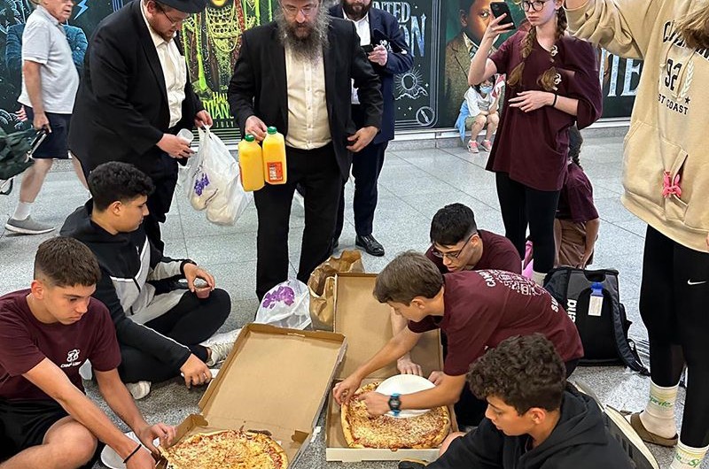 מזון גשמי ורוחני: קבוצת נערים ישראלים שנתקעו בין טיסות בשדה התעופה קנדי שבניו יורק, קיבלו סיוע במזון - פיצות ושתיה לצד הנחת תפילין מאנשי חב