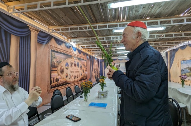בסוכה הגדולה שהוקמה בחצר בית הכנסת: חברי הקהילה היהודית בעיר פערם שברוסיה, מברכים על ד' מינים עם שליח חב