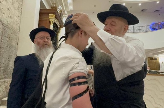 השליח הרב יצחק קוגן ממוסקבה בהנחת תפילין בבית הכנסת בלשוי ברוניא לבנו של חבר קהילתו ר' דן סלוצקי. צילום: שייע בטוויטר השליח הרב יצחק קוגן ממוסקבה בהנחת תפילין בבית הכנסת בלשוי ברוניא לבנו של חבר קהילתו ר' דן סלוצקי. צילום: שייע בטוויטר