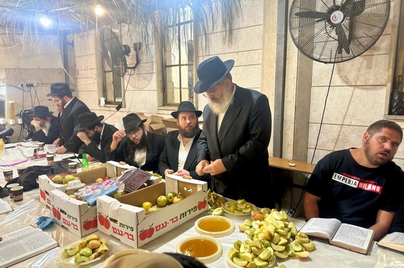 ר' בנימין ריבקין, גבאי בית הכנסת בית מנחם בחלוקת תפוח בדבש בליל הושענא רבא, לאחר אמירת ספר התהילים. צילום: ר' שמואל ריבקין