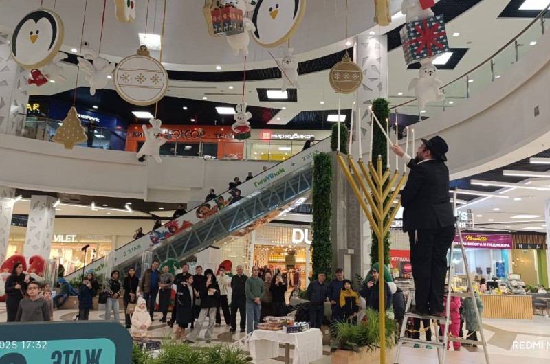 אל מול סממני חגם: הרב זלמן שמעון דערן, שליח הרבי ורב שכונת נובי-וועשקי במוסקבה, בהדלקת נר החנוכה השמיני במרכז הקניון הגדול של נובי וועשקי