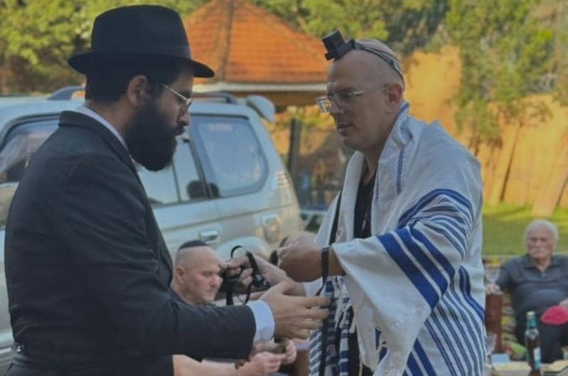 רגע לפני שגזר את שערות הראש לבנו לרגל שמחת החלאק'ה: שליח הרבי באוגנדה - הרב מוישי רסקין, מנצל את המפגש עם חברי הקהילה להנחת תפילין וזכות במצווה