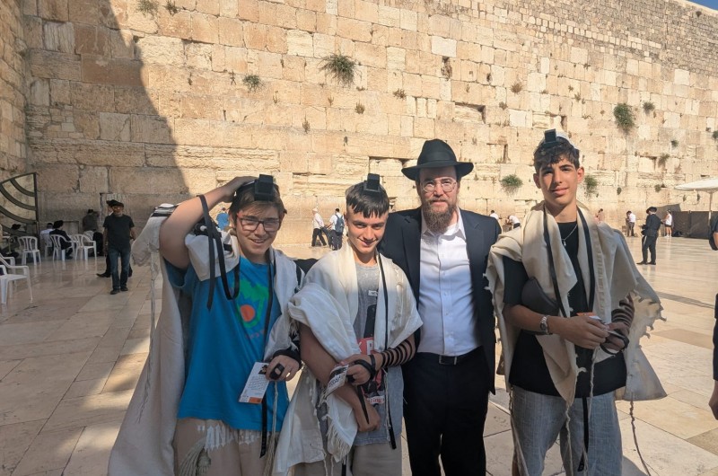 שליח הרבי לקהילה הישראלית בלונדון שבבריטניה - הרב שניאור גליצנשטיין, מניח תפילין לנערים יהודים בכותל המערבי בירושלים, לפני תפילתו בשריד בית המקדש